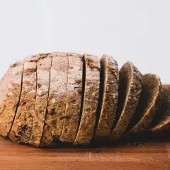 Kromki chleba razowego na desce. Zastanawiasz się, ile waży kromka chleba razowego? Ta wygląda na solidną!