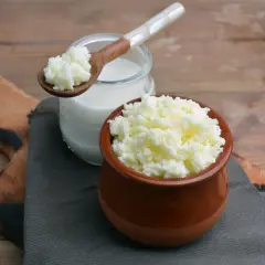 Ziarna kefirowe w glinianym naczyniu i na drewnianej łyżce. Zastanawiasz się, jaka śmietana jest najzdrowsza? Kefir to świetny wybór!