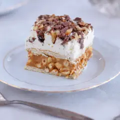 Pyszne ciasto Lion z mascarpone, przełożone chrupiącym karmelem i orzeszkami, posypane czekoladą.