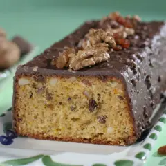 Pyszna babka z orzechami włoskimi, oblana czekoladą i ozdobiona bakaliami.