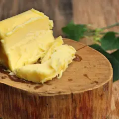 Kostka masła na drewnianym pniu. Zastanawiasz się, ile to oleju? To pyszne, żółte masło jest gotowe do użycia.