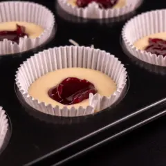 Nadziewane dżemem muffinki w papierowych foremkach w blaszce.