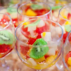 Kolorowe galaretki z owocami, w tym kiwi, w kieliszkach. Czy wiesz, dlaczego galaretka z ananasem nie tężeje?