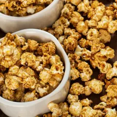 Dwie białe miseczki pełne chrupiącego popcornu karmelowego, idealnego na filmowy wieczór.