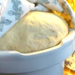 Puszyste ciasto drożdżowe rośnie pod lnianą ściereczką. Idealny czas, ile powinno rosnąć ciasto drożdżowe, to moment, gdy podwoi objętość.