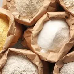 Różne rodzaje mąk w papierowych torbach. Zastanawiasz się, ile glutenu ma mąka pszenna? Tutaj znajdziesz odpowiedź.