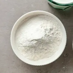 Biała miska z mąką, obok miska z brązowym cukrem i szklanka mleka. Zastanawiasz się, ile szklanek ma kilogram mąki?