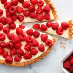 Tarta z malinami i mascarpone, ozdobiona białą czekoladą, kusi świeżością i kremowym nadzieniem.