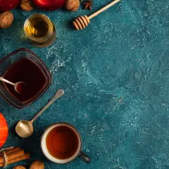 Jesienne składniki: dynie, jabłka, orzechy, cynamon i syrop pumpkin spice w miseczce.