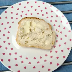 Kromka domowego chleba z masłem na talerzyku w serduszka. Zastanawiasz się, dlaczego domowy chleb się kruszy?