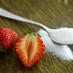 Łyżeczka cukru i truskawki na drewnianym blacie. Zastanawiasz się, ile waży kostka cukru?