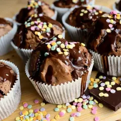Czekoladowe muffiny polane lukrem i posypane kolorową posypką. Proste sposoby, jak dekorować muffiny, by wyglądały apetycznie.