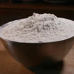 Miska pełna mąki na desce do krojenia.