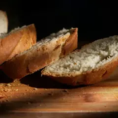 Kromki białego chleba na desce. Zastanawiasz się, ile kcal ma kromka chleba białego? Oto ona, gotowa do spożycia.