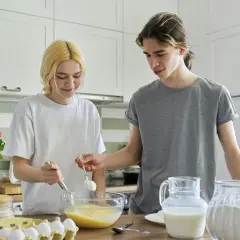 Para piecze ciasto. Dziewczyna miesza składniki, chłopak dodaje mąkę. Ile dag mąki jest w szklance?