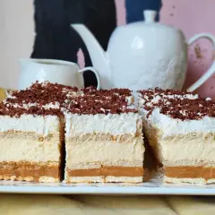 Efektowne ciasto bez pieczenia z warstwami kremu, karmelu i biszkoptów, posypane wiórkami czekolady. Idealne na deser.