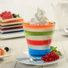 Kolorowe mini deserki z galaretką, udekorowane bitą śmietaną i owocami, kuszą swoim wyglądem.