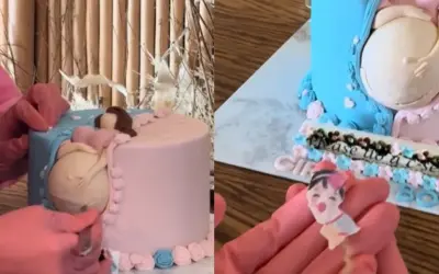 Uroczy tort na baby shower z figurką ciężarnej kobiety. Dekoracja w kolorach różowym i niebieskim, z napisem "Please us a sec".