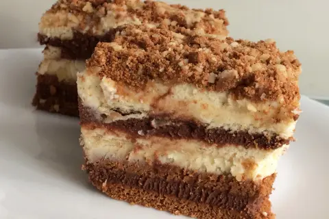 Warstwowe ciasta bez pieczenia z mascarpone, przełożone kremem czekoladowym i posypane kruszonką. Idealne na deser.
