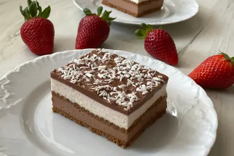 Pyszne ciasto z mascarpone bez pieczenia, warstwowe, z polewą czekoladową i wiórkami kokosowymi. Obok świeże truskawki.