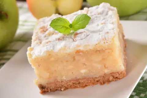 Pyszne, ekspresowe ciasto z jabłkami, posypane cukrem pudrem i udekorowane listkiem mięty. Idealne na szybki deser.