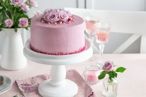 Elegancki tort urodzinowy dla kobiety, udekorowany różami i posypką. Idealny na wyjątkową okazję.