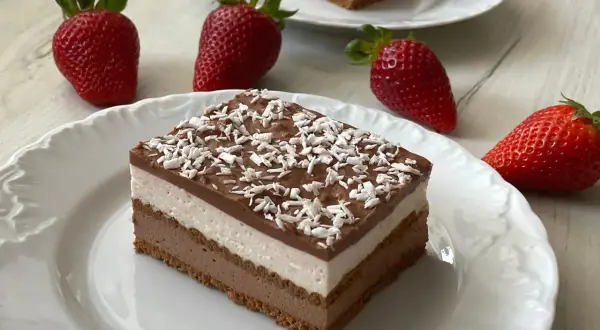 Pyszne ciasto z mascarpone bez pieczenia, warstwowe, z polewą czekoladową i wiórkami kokosowymi. Obok świeże truskawki.