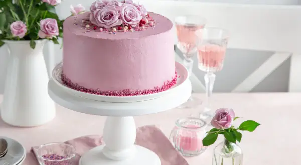 Elegancki tort urodzinowy dla kobiety, udekorowany różami i posypką. Idealny na wyjątkową okazję.