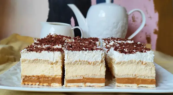 Efektowne ciasto bez pieczenia z warstwami kremu, karmelu i biszkoptów, posypane wiórkami czekolady. Idealne na deser.
