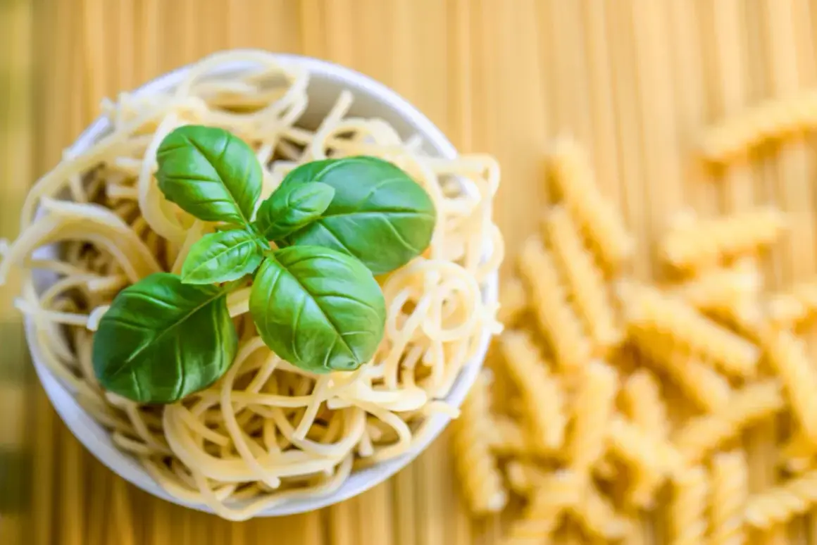 Miseczka spaghetti z bazylią, obok rozsypane fusilli. To klasyczne danie, gdzie co to jest semolina z pszenicy durum, stanowi podstawę.