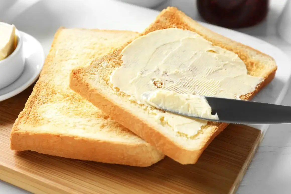 Na desce leżą dwa tosty. Na jednym z nich nóż rozsmarowuje masło. Ile gram ma kromka chleba tostowego?