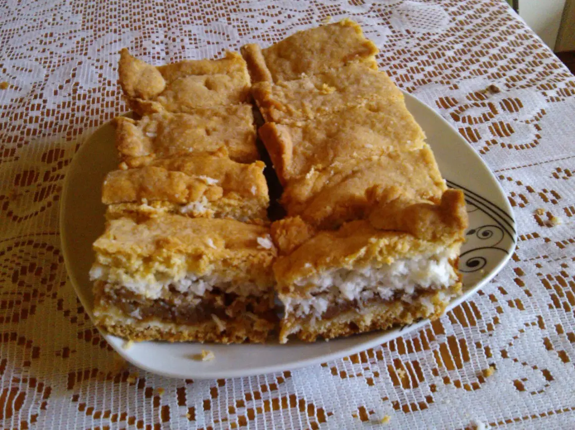 Pyszne ciasto z jabłkami i kokosem, pokrojone na kawałki, leży na talerzu.