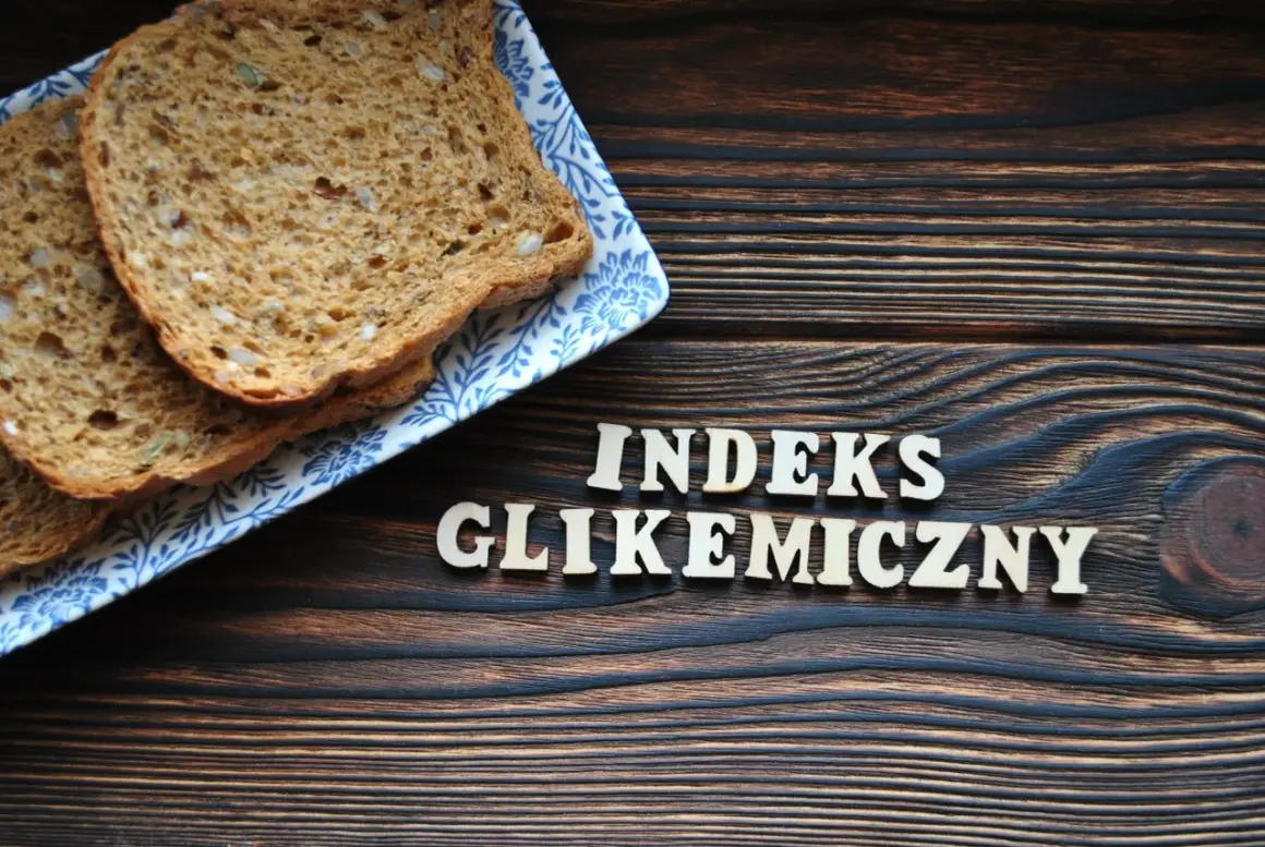 Plasterki chleba pełnoziarnistego na talerzyku z niebieskim wzorem. Obok drewniane litery układają się w napis "INDEKS GLIKEMICZNY".
