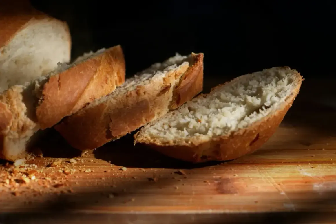 Kromki białego chleba na desce. Zastanawiasz się, ile kcal ma kromka chleba białego? Oto ona, gotowa do spożycia.