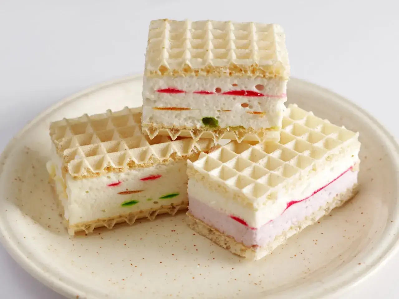 Wafle z galaretką i śmietaną – pyszny przepis na deser. Warstwy kremu przełamane kolorowymi kawałkami galaretki.