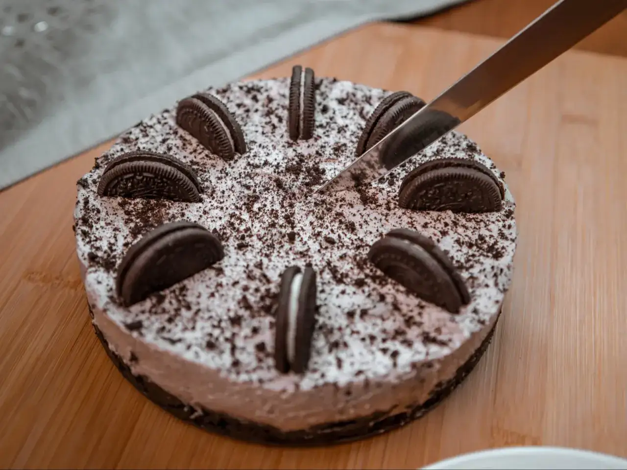 Sernik oreo na zimno, udekorowany ciasteczkami i pokruszonymi oreo, kroimy nożem.