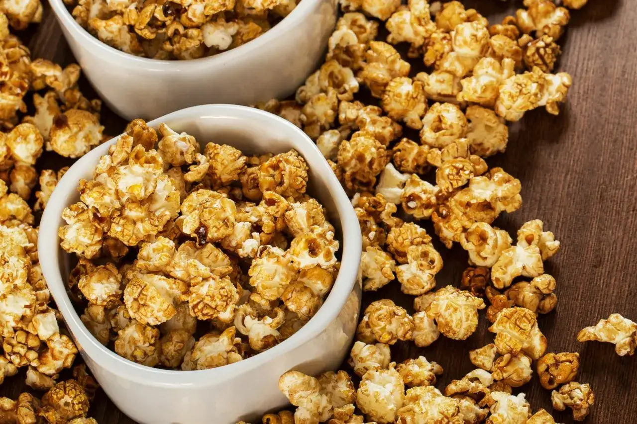 Dwie białe miseczki pełne chrupiącego popcornu karmelowego. Idealny przepis na to, jak zrobić popcorn karmelowy.