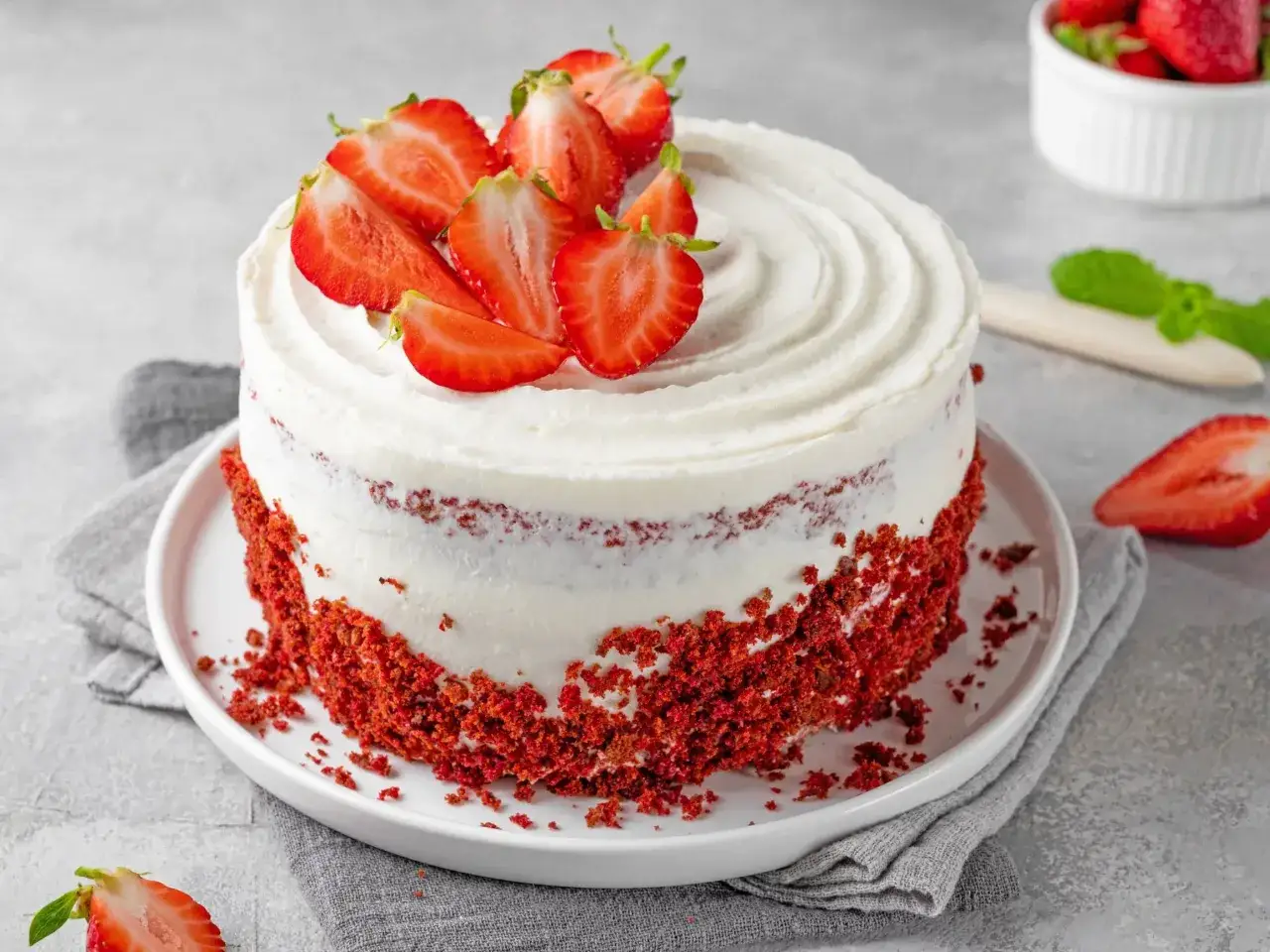 Pyszny tort Red Velvet z kremem i świeżymi truskawkami na wierzchu. Wygląda jak tort z sercem, gotowy na specjalną okazję.