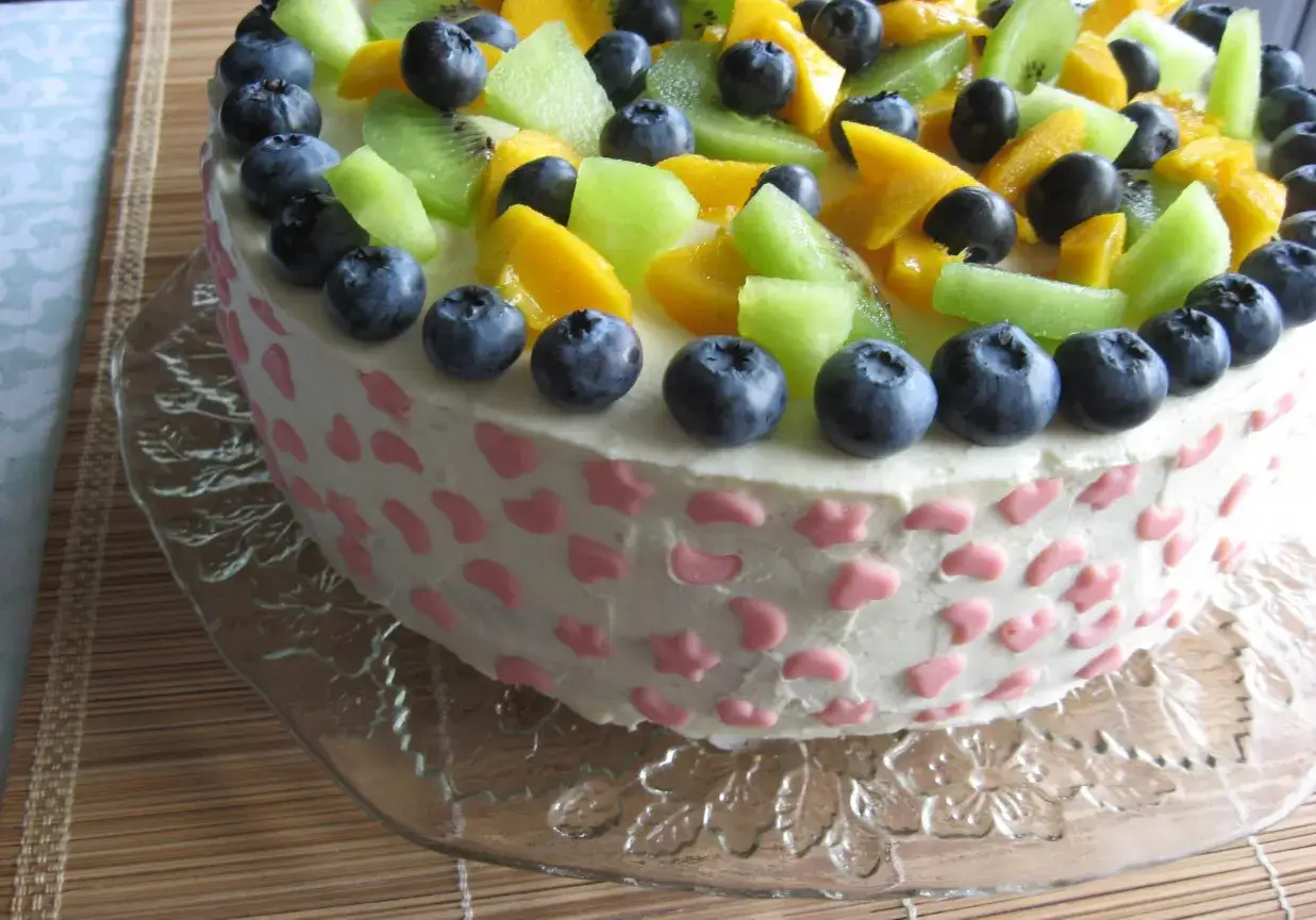 Pyszny tort z owocami i kremem do tortu z mascarpone, ozdobiony jagodami, kiwi i mango.