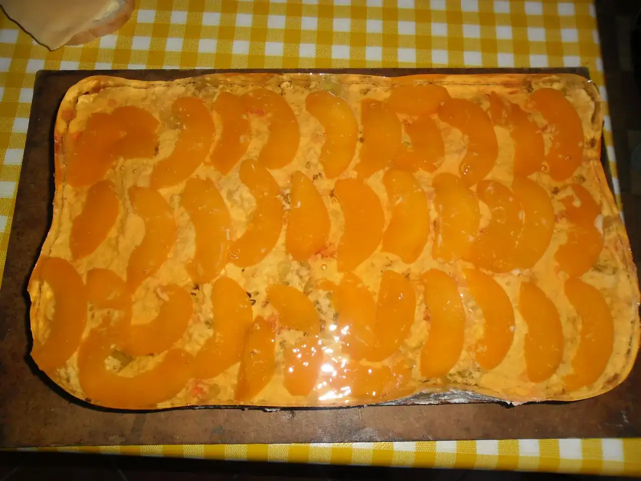 Pyszne ciasto brzoskwiniowe, ułożone z kawałków brzoskwiń w galaretce, wygląda jak prawdziwa pychotka.