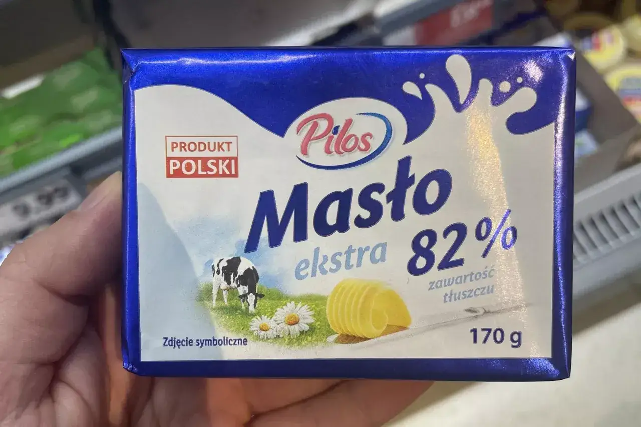 Kostka masła Pilos ekstra 82% zawiera 170 gramów. Produkt polski z krową na łące.