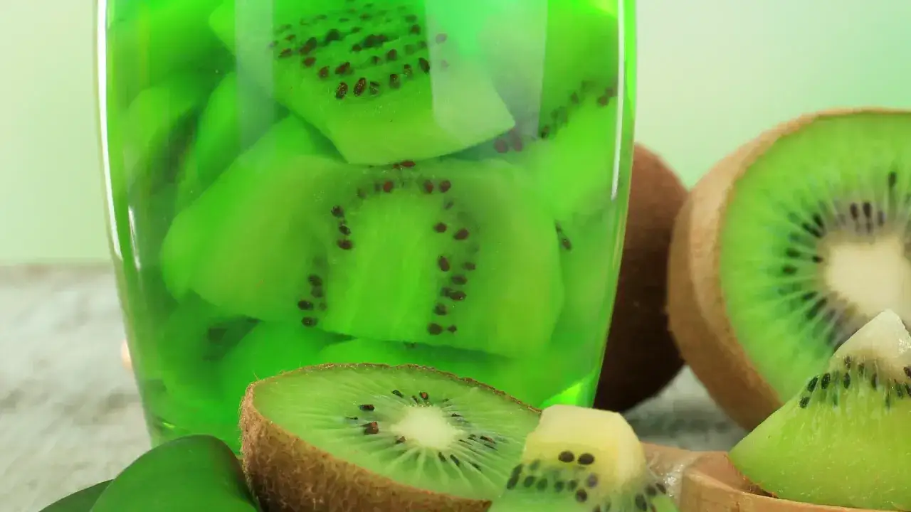 Zielona galaretka z kawałkami kiwi w szklance. Obok leżą przekrojone owoce. Zastanawiasz się, dlaczego galaretka nie tężeje z kiwi?