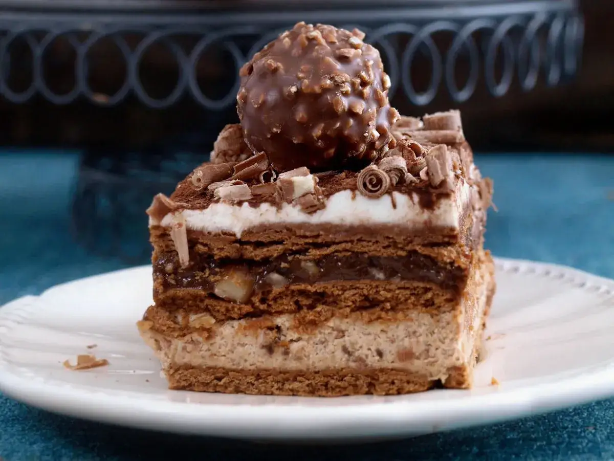 Pyszne ciasto Ferrero Rocher z warstwami czekolady, kremu i orzechów, zwieńczone całą czekoladką.
