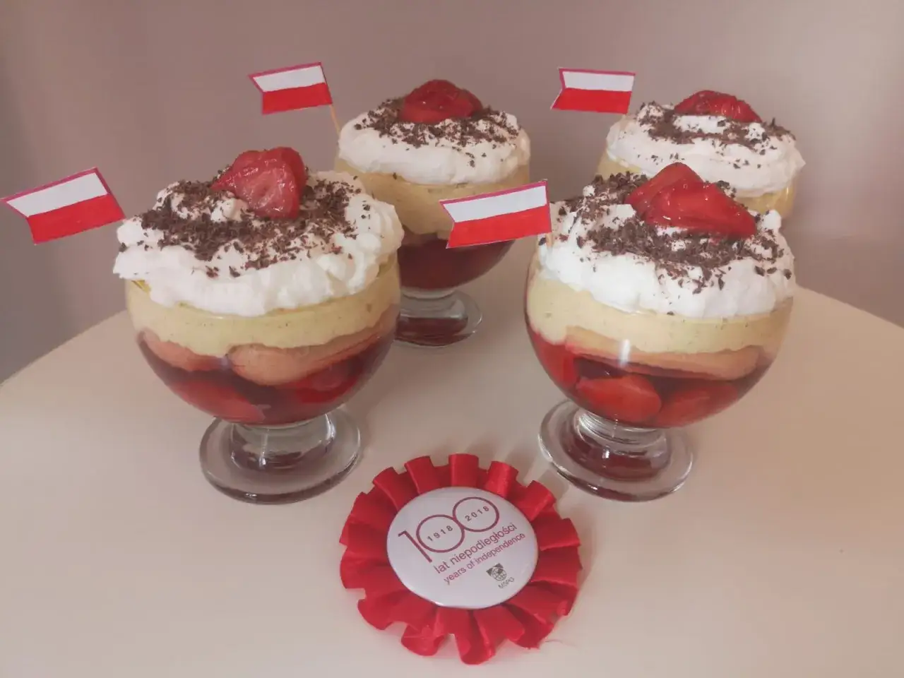 Deser z truskawkami i bitą śmietaną, ozdobiony polskimi flagami. Idealny, gdy zastanawiasz się, czy rozmrażać truskawki do galaretki.