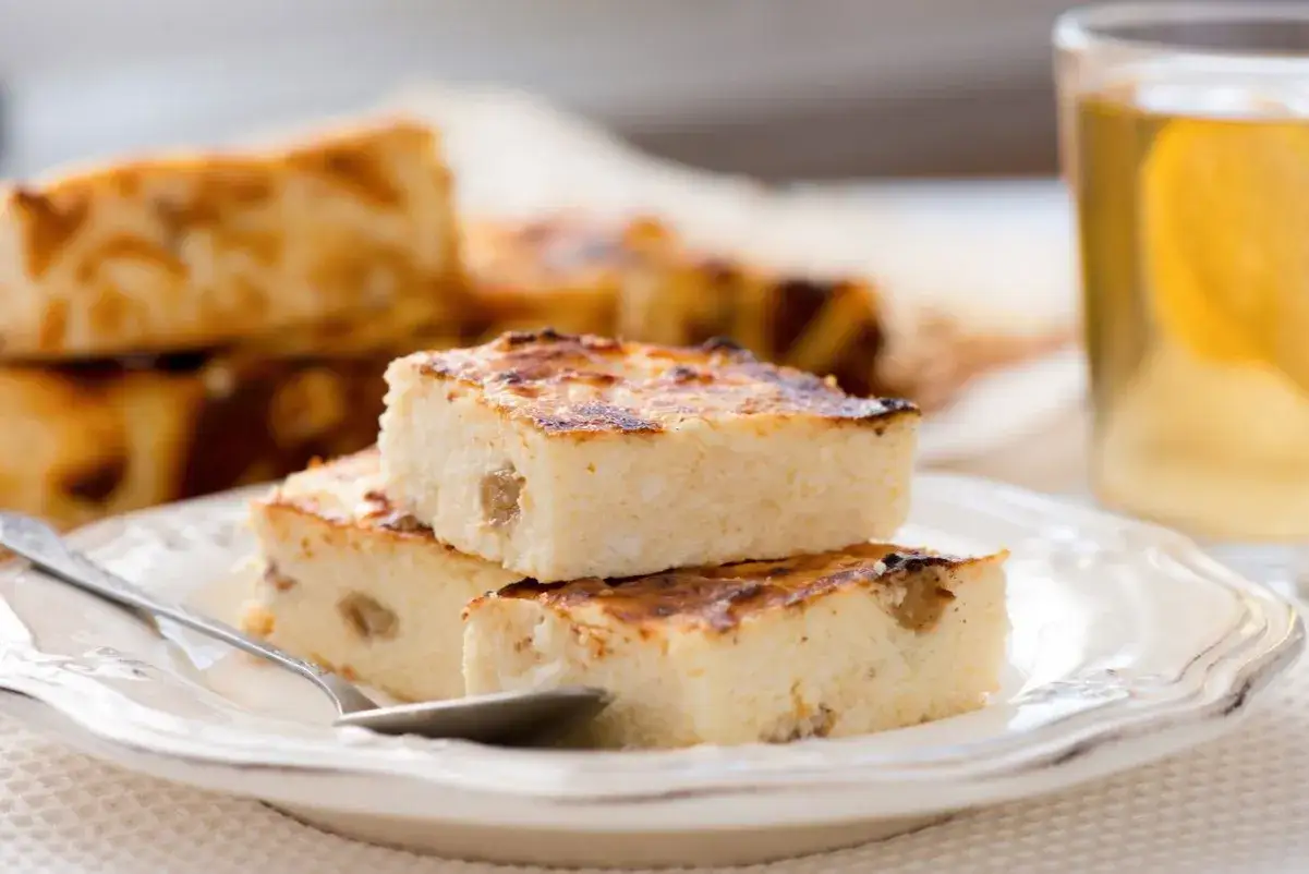 Pyszny sernik, idealny do pieczenia w piekarniku, podany na talerzu z herbatą.