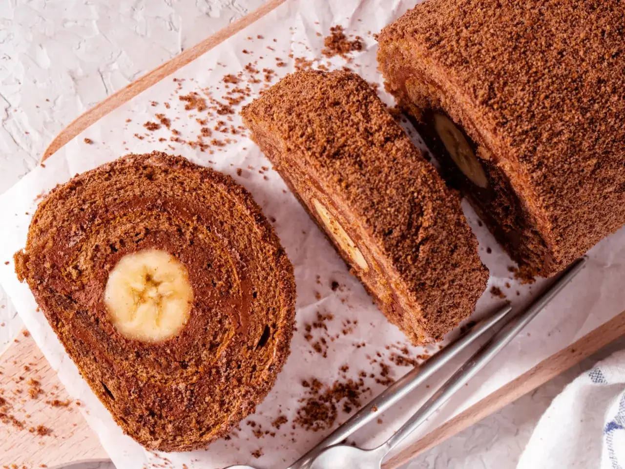 Pyszna rolada biszkoptowa czekoladowa z bananem w środku, posypana kakaową posypką. Idealna na deser.