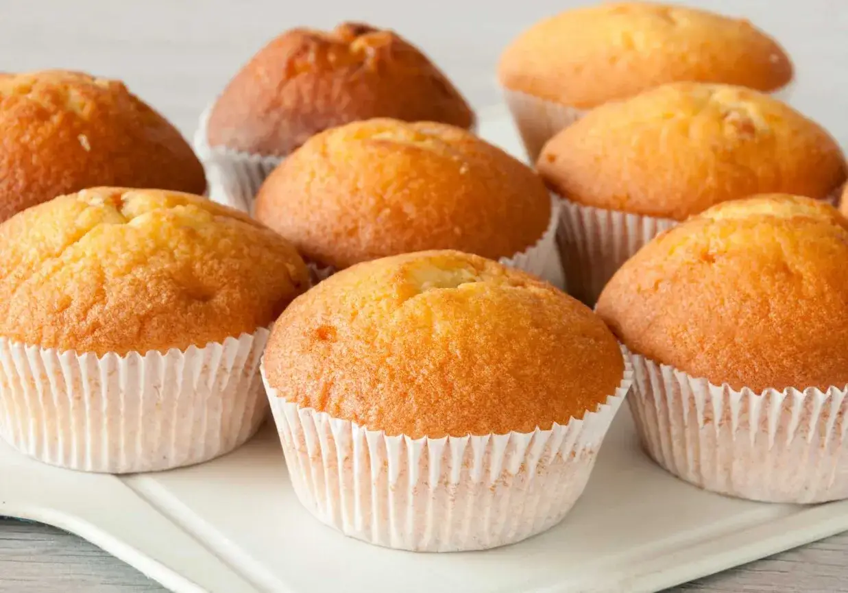 Złociste muffinki w papierowych foremkach, idealne na podwieczorek. Zastanawiasz się, jak długo piec muffinki, by były tak puszyste?