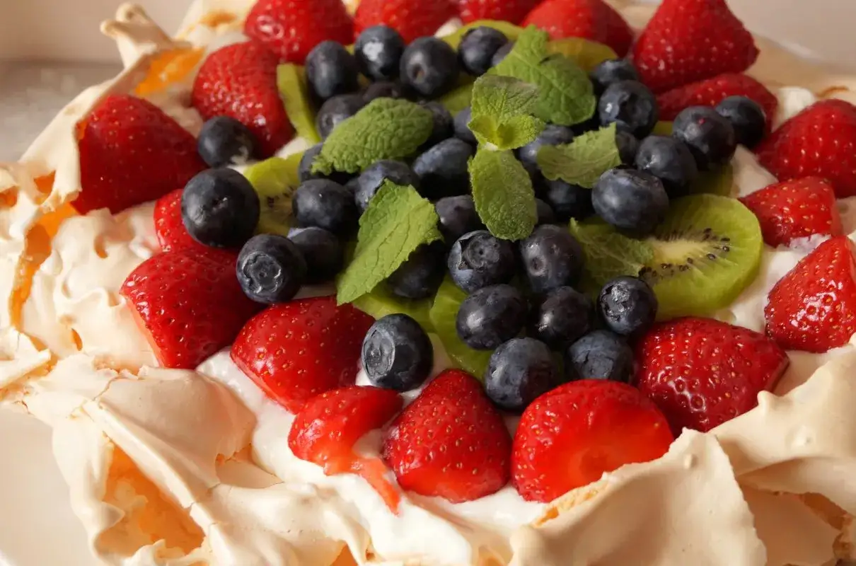 Beza Pavlova z mascarpone, udekorowana truskawkami, borówkami, kiwi i miętą. Pyszny deser na letnie popołudnie.
