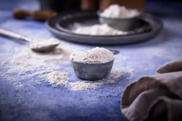 Mąka w miarkach na niebieskim blacie. Zastanawiasz się, ile szklanek mąki jest w kilogramie?