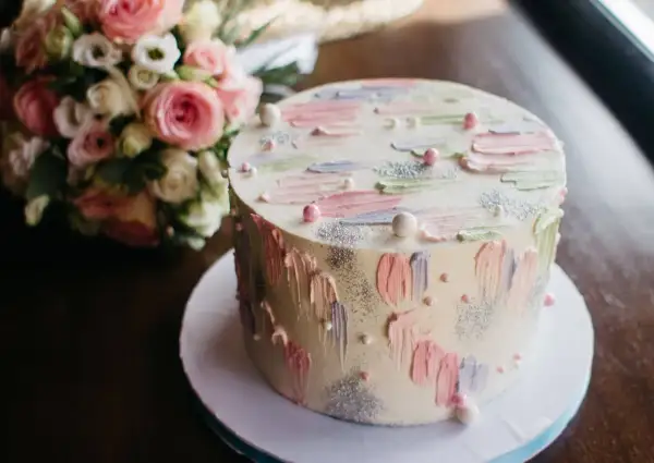 Oto tort weselny z pastelowymi pociągnięciami pędzla i brokatem. Trudno zgadnąć, ile waży tort, ale wygląda na pyszny!
